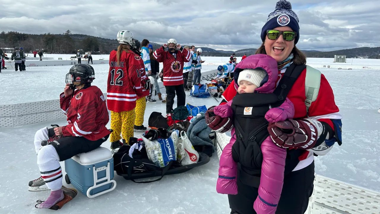 Mutter mit Baby vor Pond-Hockey-Spielern auf dem Natureis