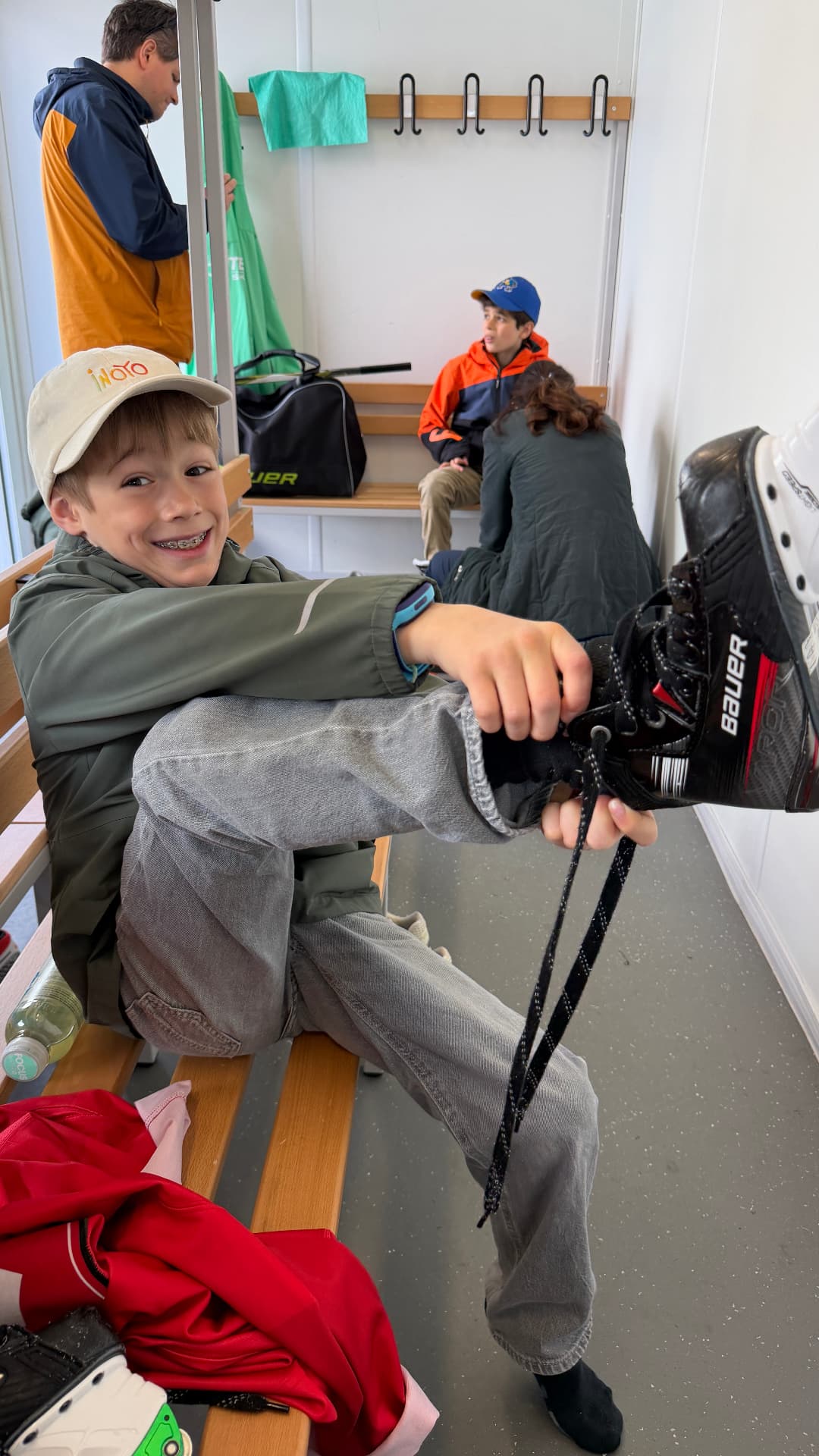 Junge zieht sich in der Umkleide einen Eishockeyschlittschuh an